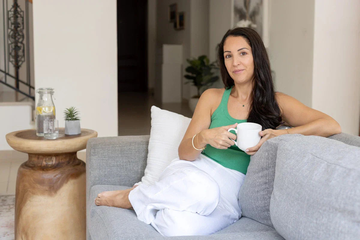 Marie Rino, founder of Pure Path, sitting on a sofa in a bright, natural home, enjoying a cup of tea — reflecting her journey as a UAE mum embracing a non-toxic lifestyle and creating Pure Path.