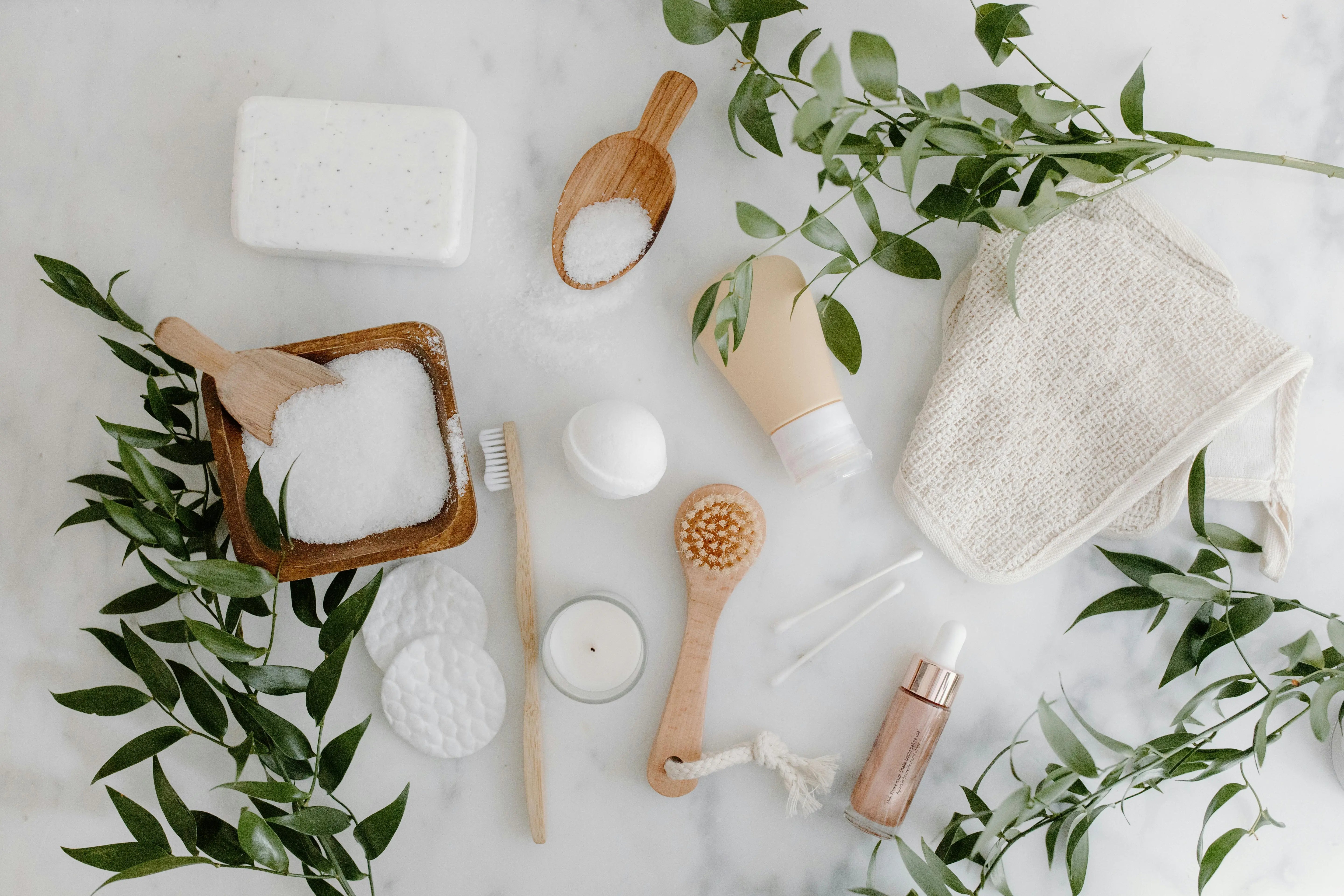 A minimalist flat lay of sustainable self-care and cleaning essentials made from natural materials, styled with greenery to reflect a clean, non-toxic lifestyle.